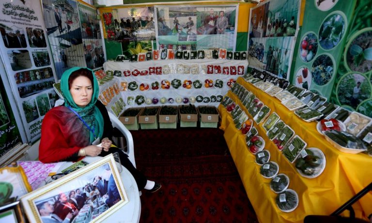 A woman sits in front of a store displaying goods.